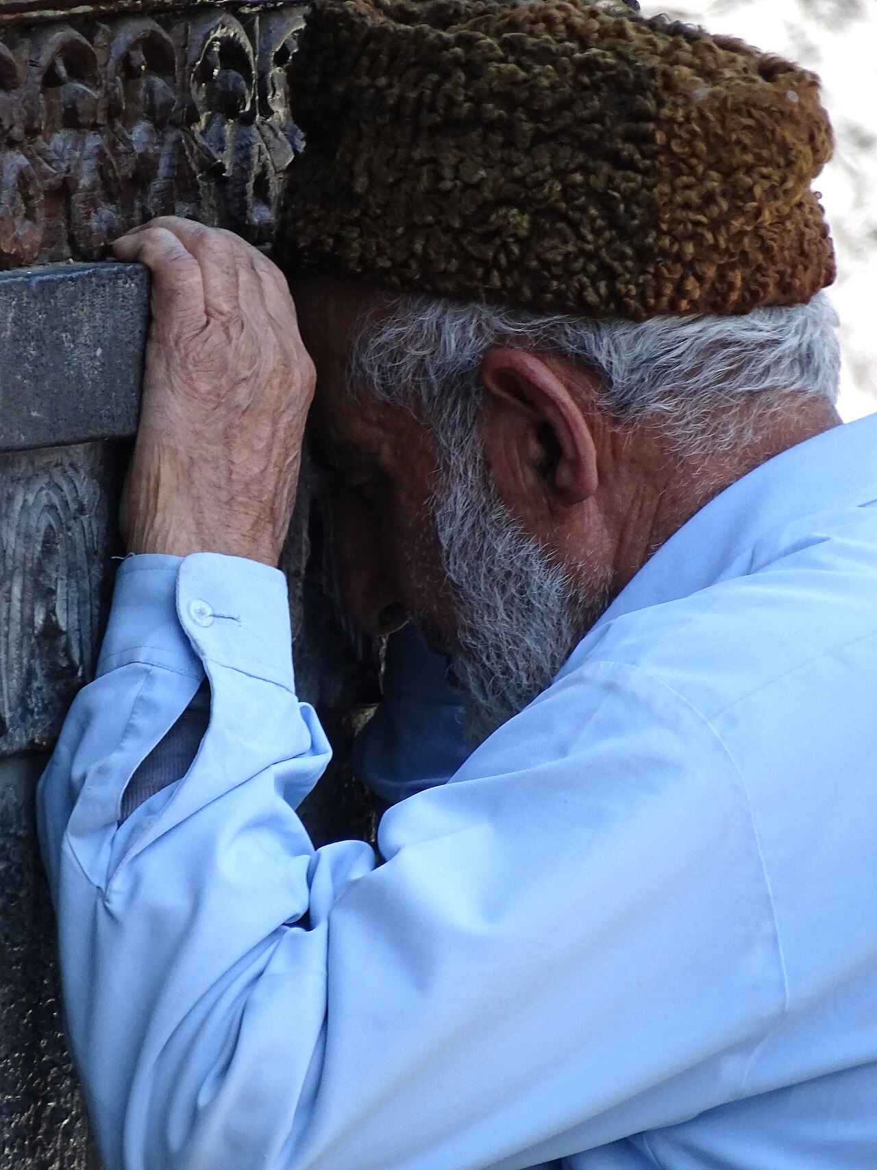 مصلٍّ كبير في السن مستنداً إلى منبر خشبي